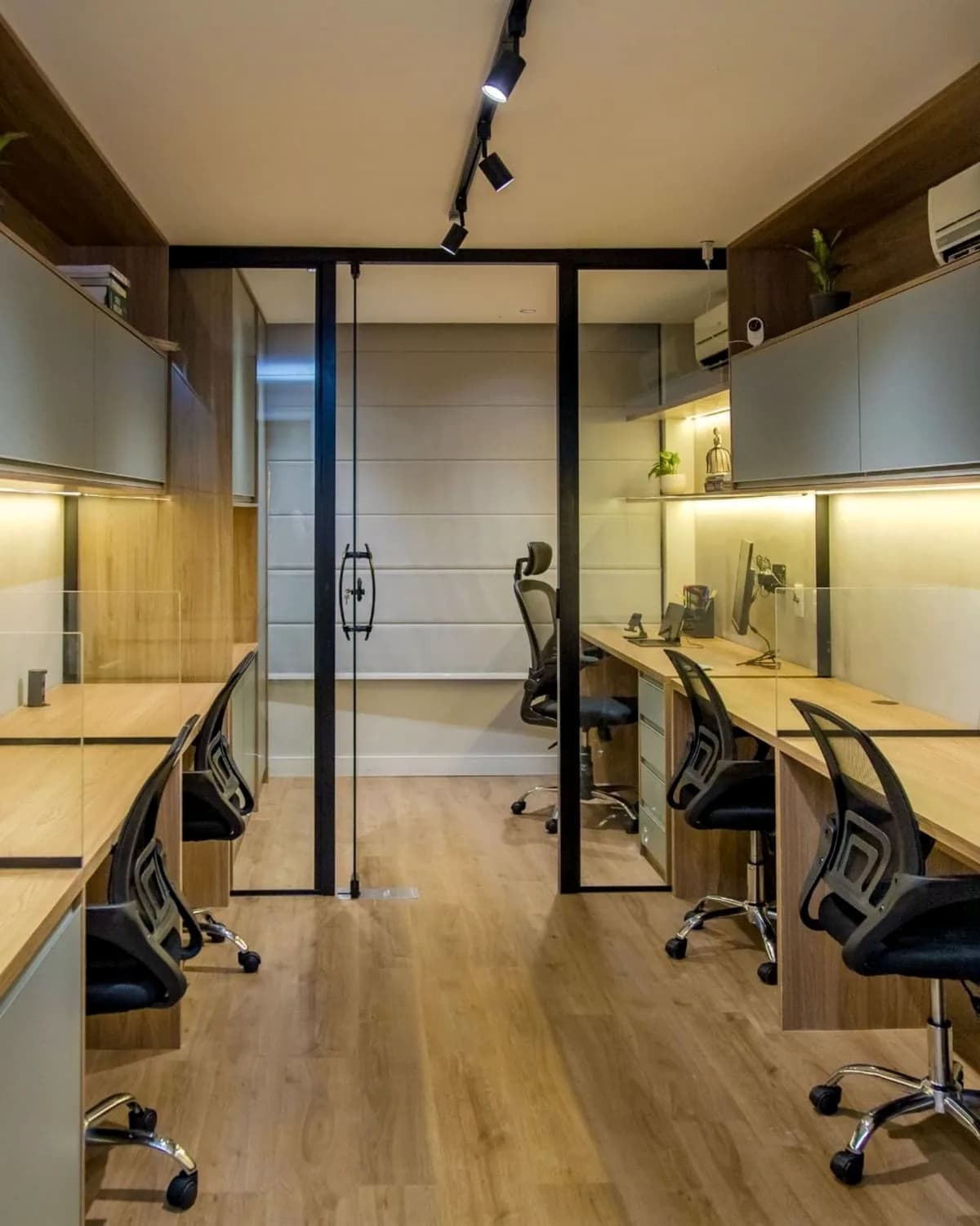 Desks along both walls of a narrow room, a glazed door at the end.