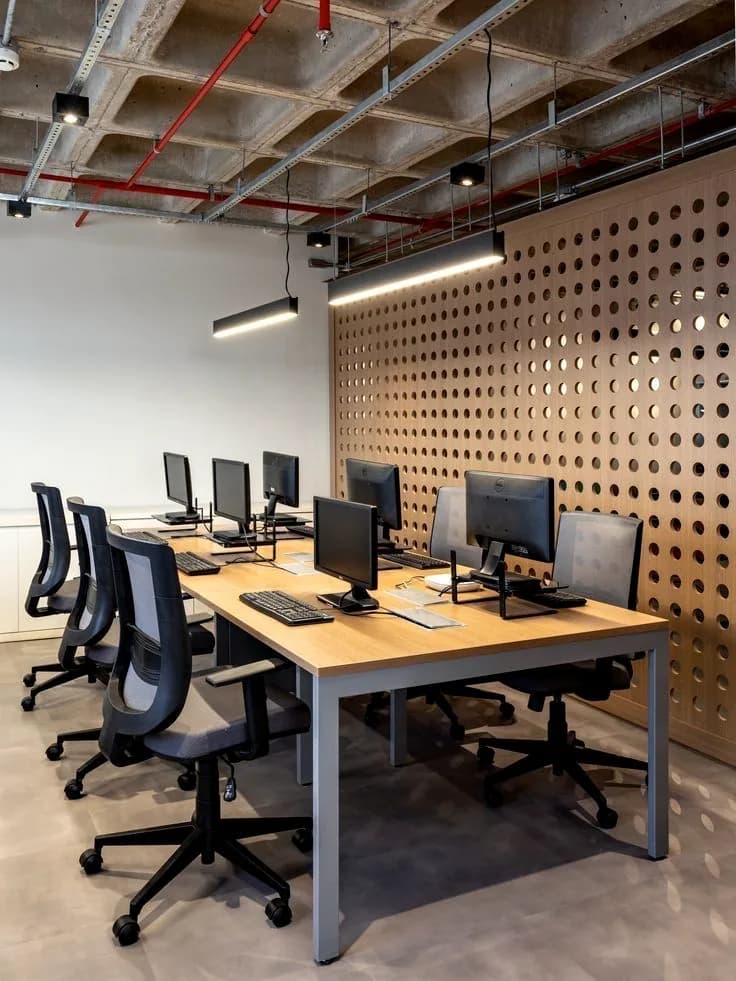 Backlit perforated timber wall under a concrete waffle ceiling.