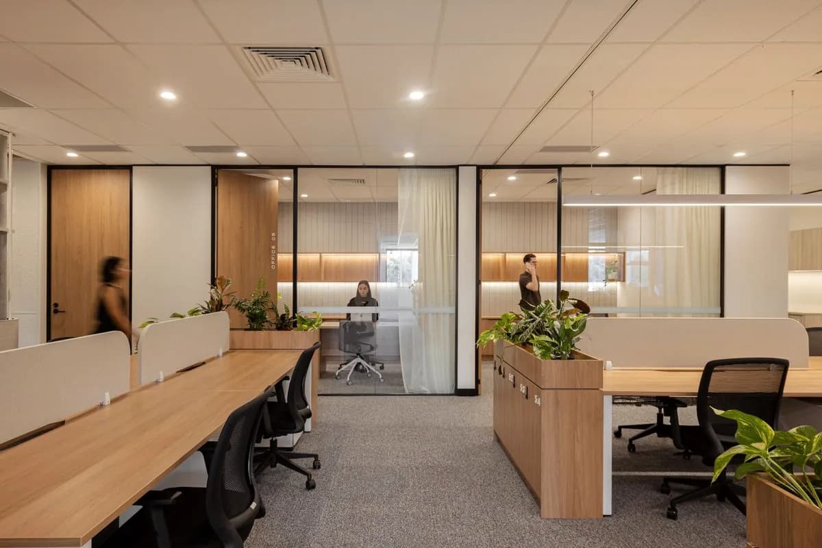 Open plan desks beside glazed meeting rooms, one person walking past.