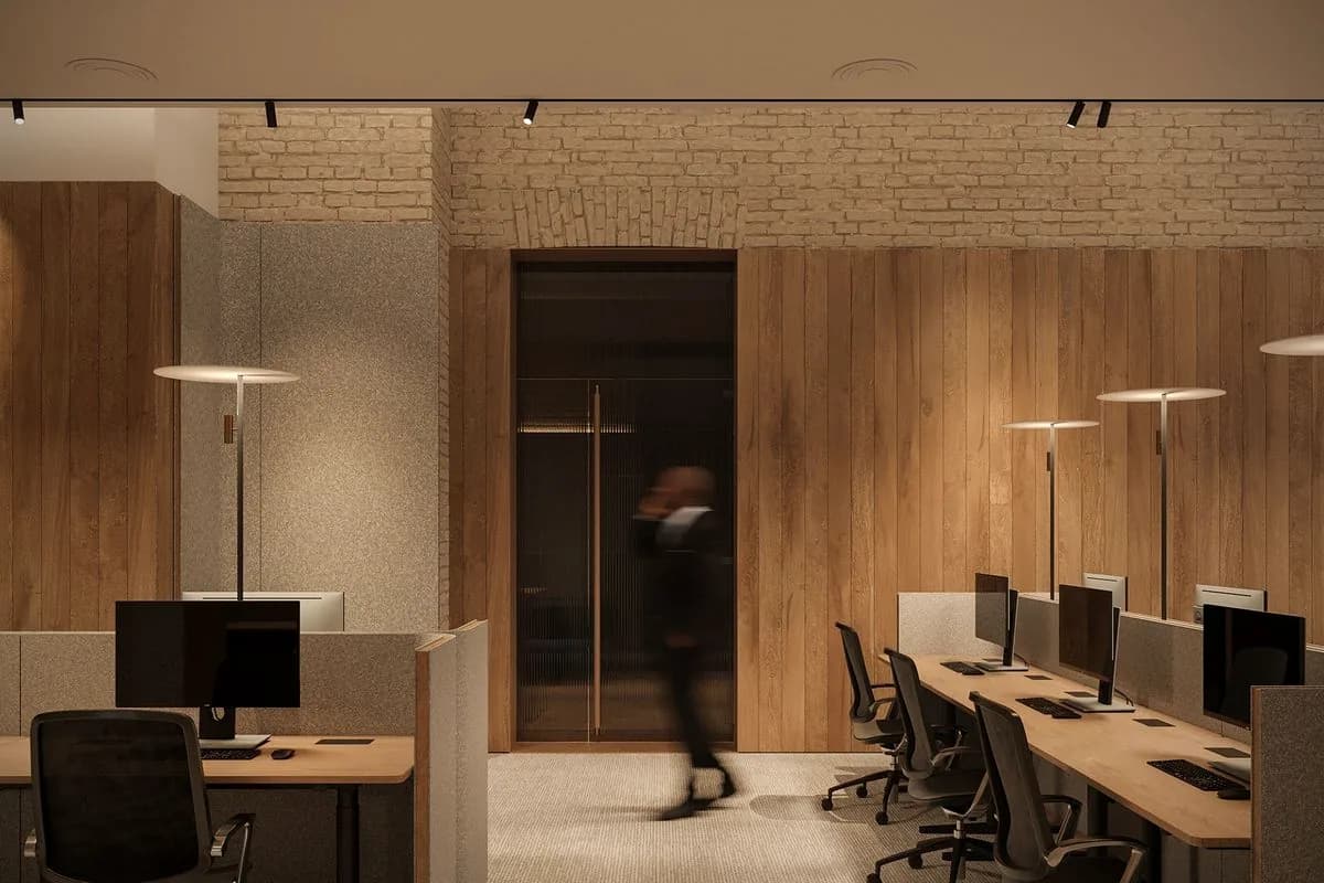 Brick and timber slat wall, one figure standing in a lit doorway.